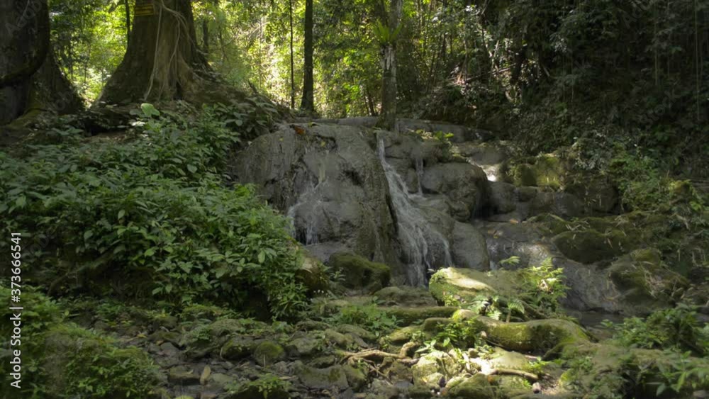 Scenery of waterfall flowing through the rock among lush foliage vegetation. Fresh water flows from cascade in tropical forest during summer. Sa Nang Manora Forest Park. Thailand. Scenery of waterfall flowing through the rock among lush foliage vegetation. Fresh water flows from cascade in tropical forest during summer. Sa Nang Manora Forest Park. Thailand.