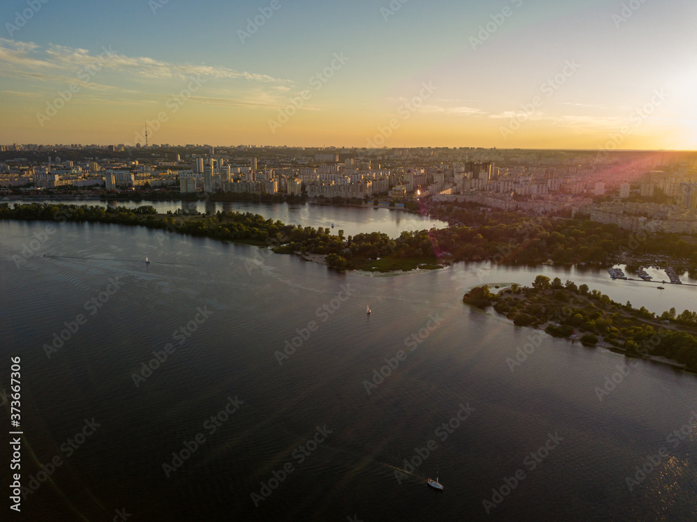 Fototapeta premium Aerial drone view. Bank of the Dnieper River in Kiev in the evening in the rays of the setting sun.