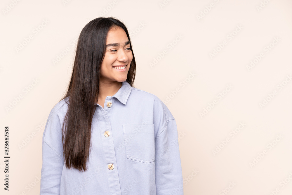 Young Indian woman isolated on beige background looking to the side and smiling Young Indian woman isolated on beige background looking to the side and smiling