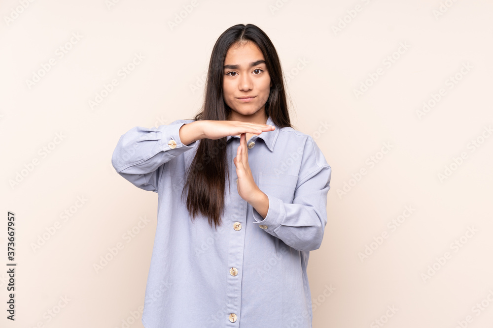 Young Indian woman isolated on beige background making time out gesture Young Indian woman isolated on beige background making time out gesture