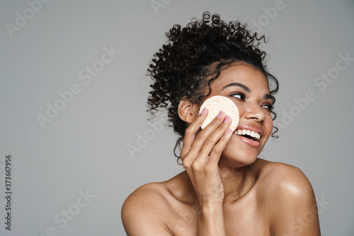 Image of african american woman smiling and using cleansing sponge