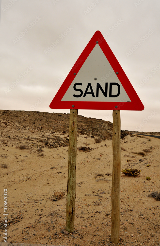 A warning road sign on a road through a section of the Namib Desert where the sand blows across the road
