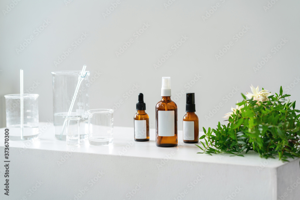 Light cosmetic background. Vials, glass laboratory flasks on the table. Natural cosmetics concept.