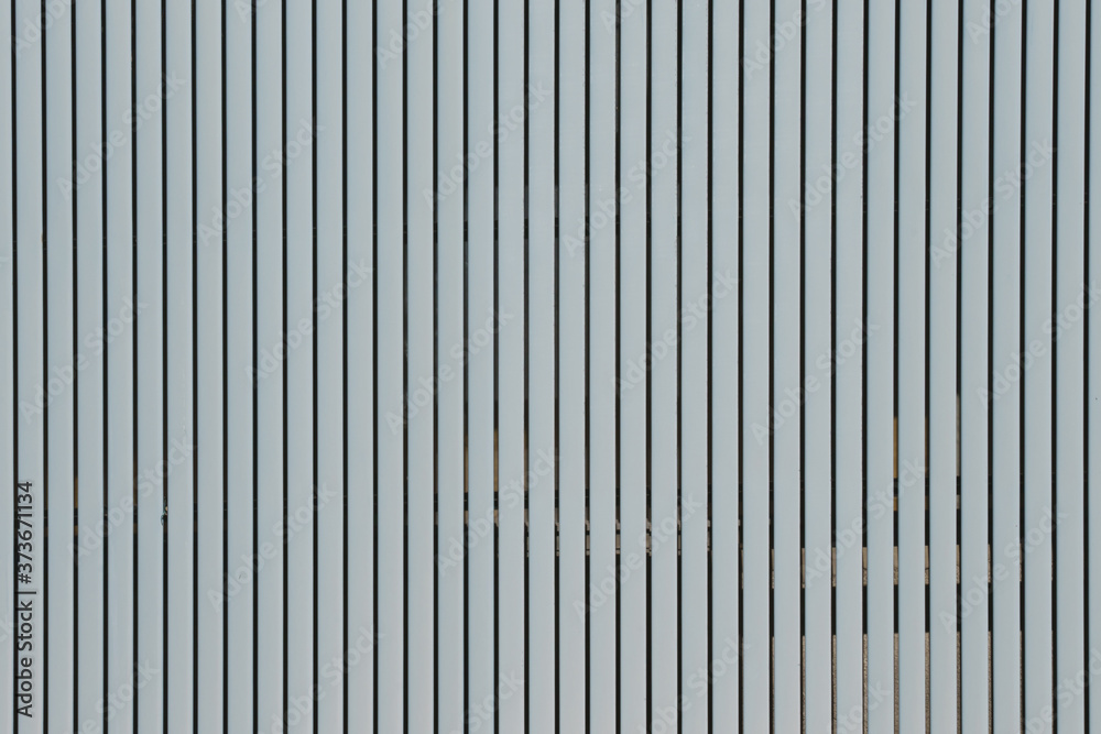 Wall made of strips of gray aluminum profile. Vertical lines. Wall made of strips of gray aluminum profile. Vertical lines.