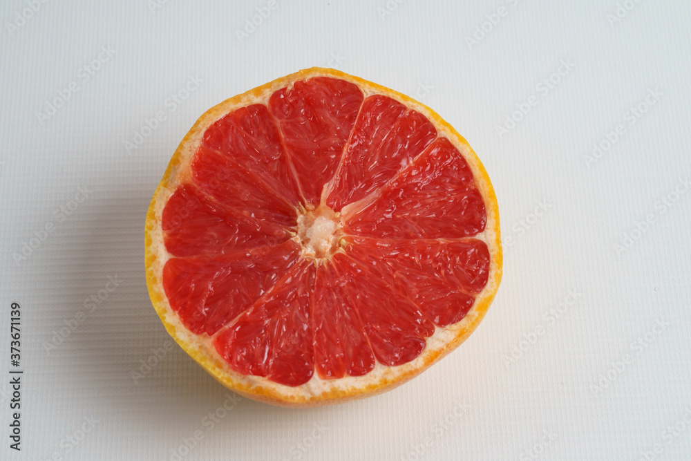 Half a ripe grapefruit on a white plate. Closeup. Half a ripe grapefruit on a white plate. Closeup.