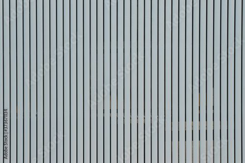 Wall made of strips of gray aluminum profile. Vertical lines.