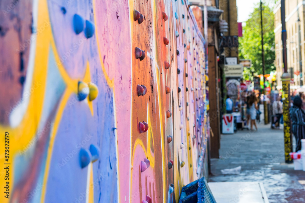 Fototapeta premium Kolorowa sztuka uliczna na stalowej kratownicy wiaduktu na tętniącej życiem londyńskiej ulicy Brick Lane