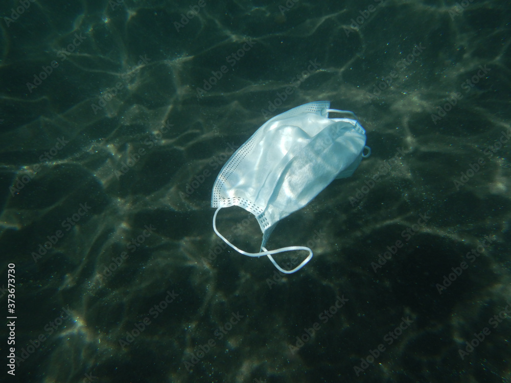 Fototapeta premium Disposable coronavirus face mask floating in the Sea. The Canary Islands. Covid-19 pollution.
