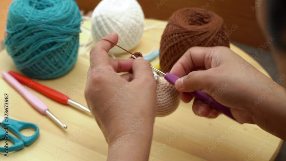 Crocheting Amigurumi technique, close up footage of woman's hands making amigurumi doll using crochet stitches, recorded in 4K resolution