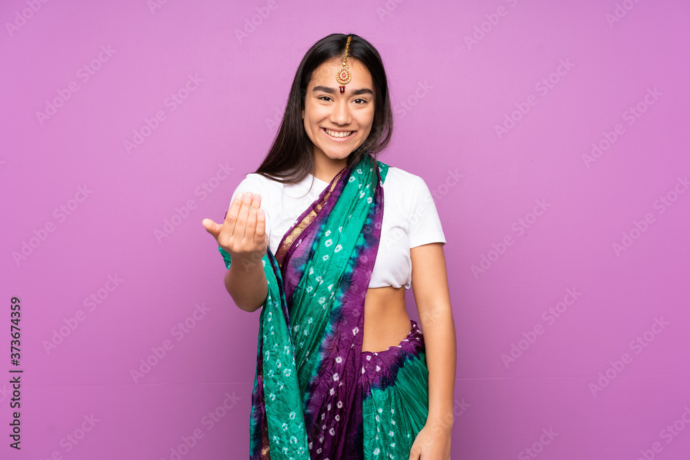 Young Indian woman with sari over isolated background inviting to come with hand. Happy that you came Young Indian woman with sari over isolated background inviting to come with hand. Happy that you came