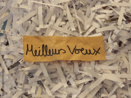 Best wishes handwritten in French on brown paper in a pile of paper shreds 