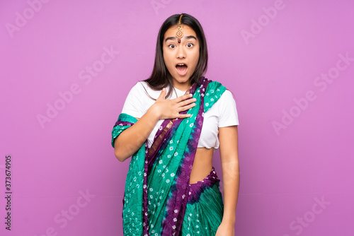 Young Indian woman with sari over isolated background surprised and shocked while looking right