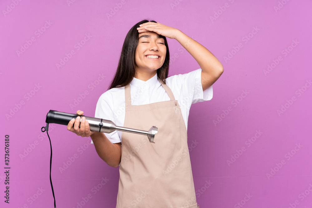 Indian woman using hand blender isolated on purple background laughing Indian woman using hand blender isolated on purple background laughing