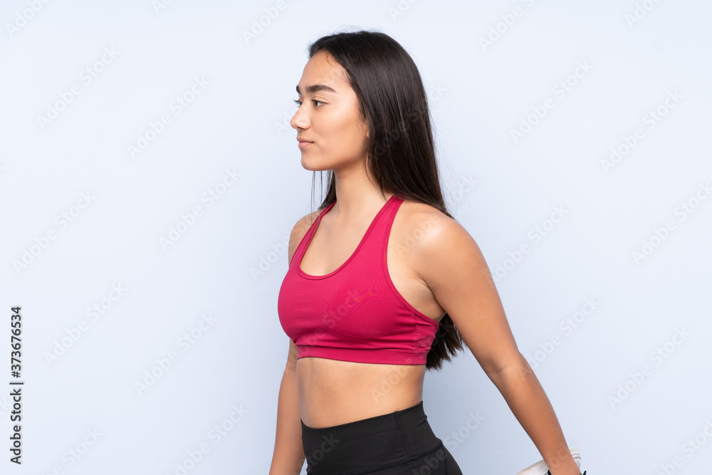 Young Indian sport woman isolated on blue background stretching leg Young Indian sport woman isolated on blue background stretching leg