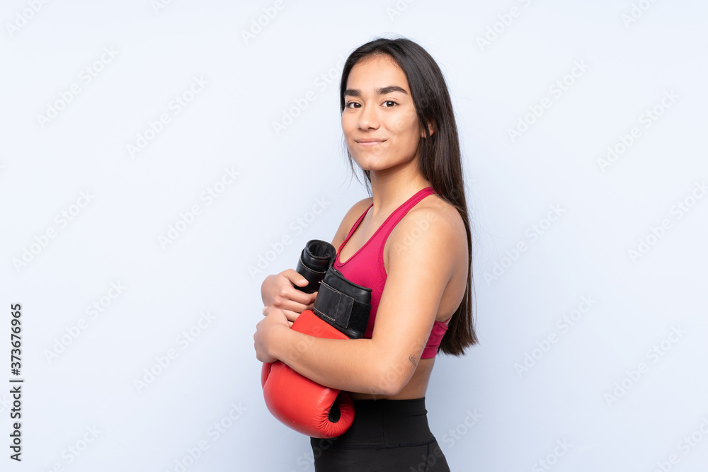 Young Indian sport woman isolated on blue background with boxing gloves Young Indian sport woman isolated on blue background with boxing gloves
