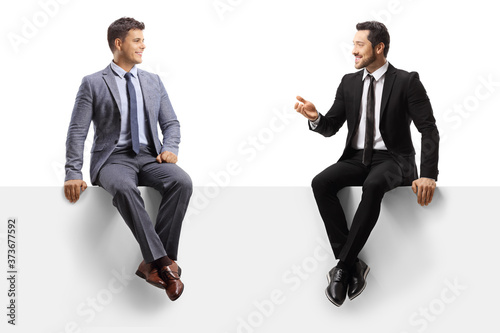Men sitting on a blank panel and having a conversation