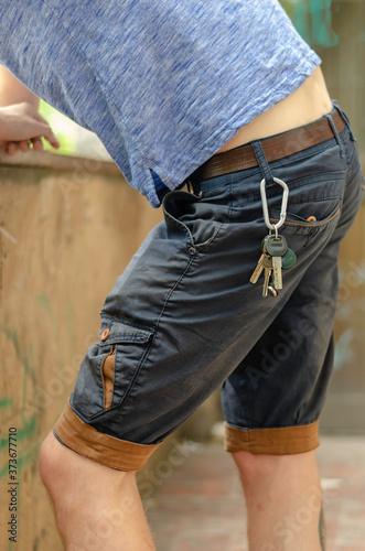 Young man stands in the street with his elbows on stone fence.