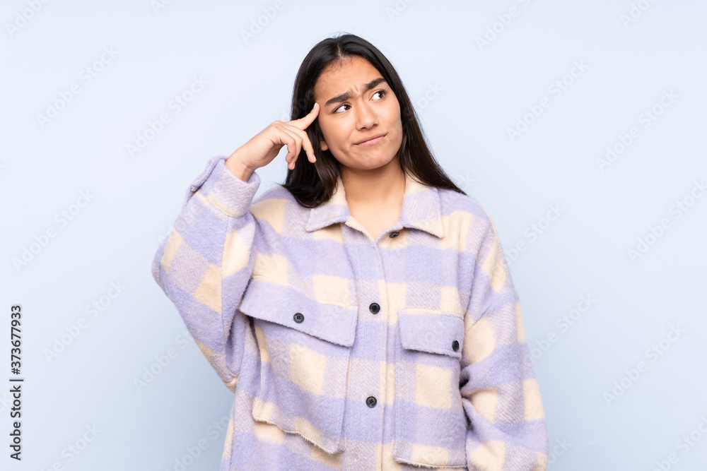 Young Indian woman isolated on blue background making the gesture of madness putting finger on the head Young Indian woman isolated on blue background making the gesture of madness putting finger on the head