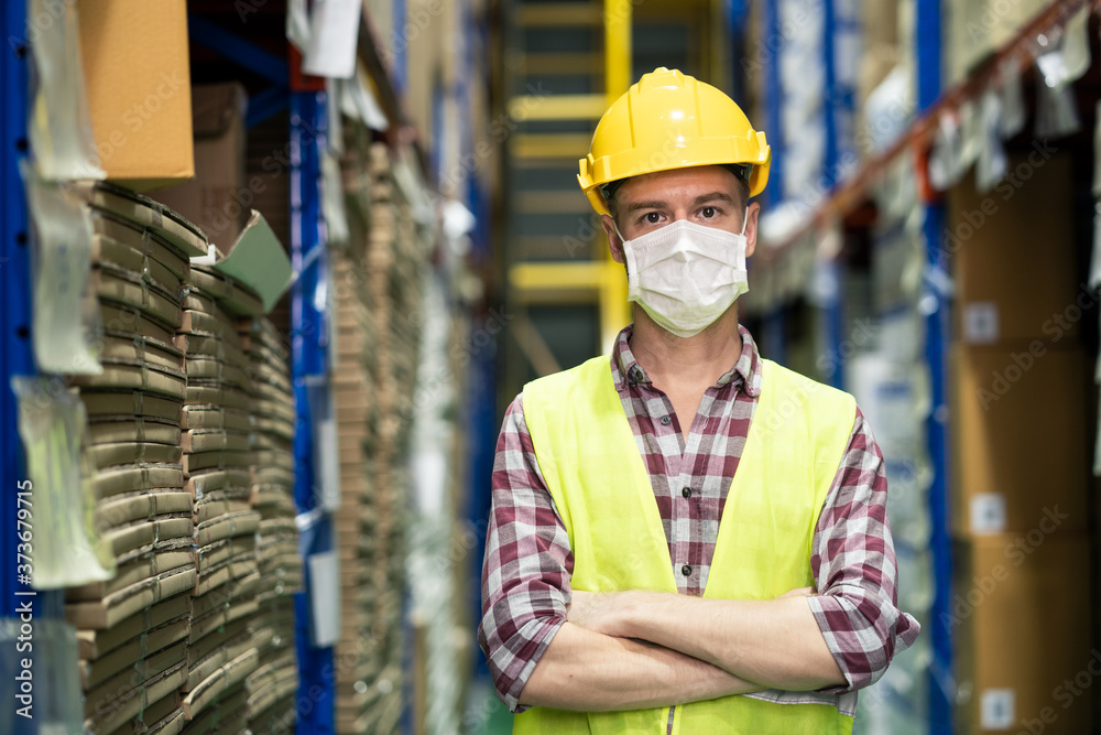 Male engineer worker wear mask work during COVID in warehouse. Male engineer worker wear mask work during COVID in warehouse.