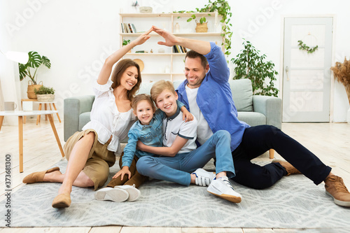 Parents Making Symbolic Roof Joining Hands Above Kids Sitting Indoors photo