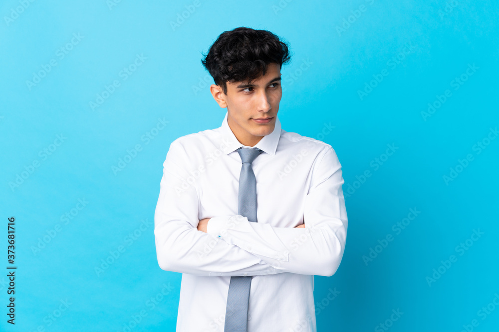 Young Argentinian businessman over isolated blue background thinking an idea Young Argentinian businessman over isolated blue background thinking an idea