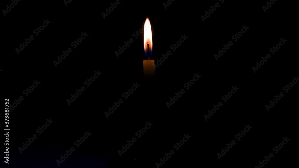 Close up single burning, bright white paraffin candle light on isolated dark black background. Red, orange, yellow candle fire flame smoke in party festival celebration at night. Copy space for text. Close up single burning, bright white paraffin candle light on isolated dark black background. Red, orange, yellow candle fire flame smoke in party festival celebration at night. Copy space for text.