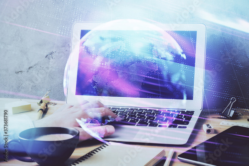 Technology theme hologram with man working on computer on background. High tech concept. Multi exposure.