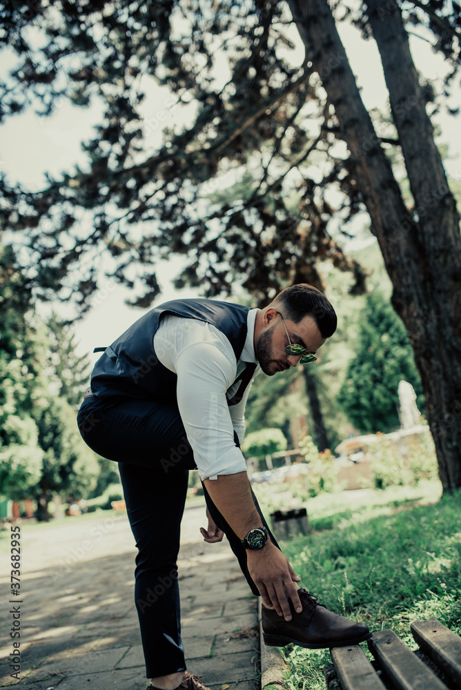 a young sexy businessman in a suit cleaning his shoes a young sexy businessman in a suit cleaning his shoes