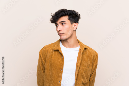 Young Argentinian man over isolated background making doubts gesture looking side
