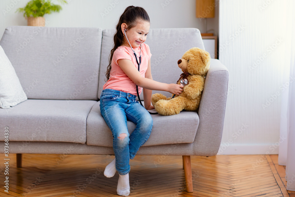 Asian kid girl playing doctor treating bear toy at home Asian kid girl playing doctor treating bear toy at home