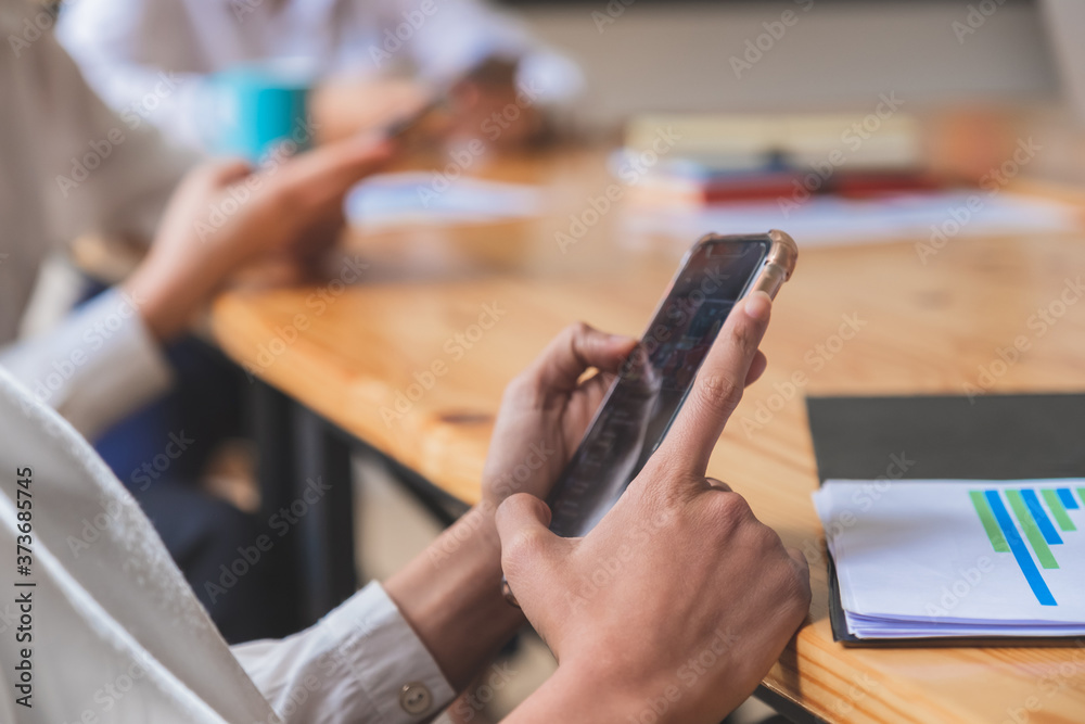 Close-up shot of group of people using smart phone while sitting together