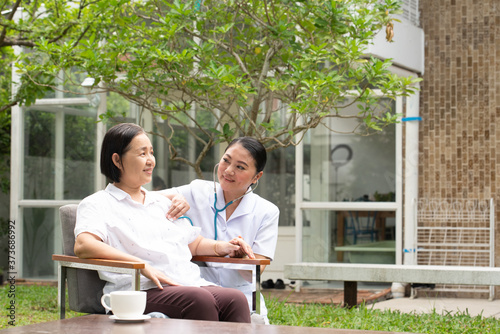 Female Caretaker With Senior Woman In Yard