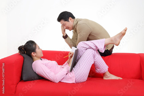 South East Asian young woman man lying sitting on red sofa talk look romance white background