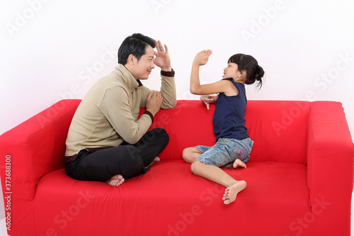 South East Asian young father daughter parent girl child on red sofa playing fun happy smile on white background