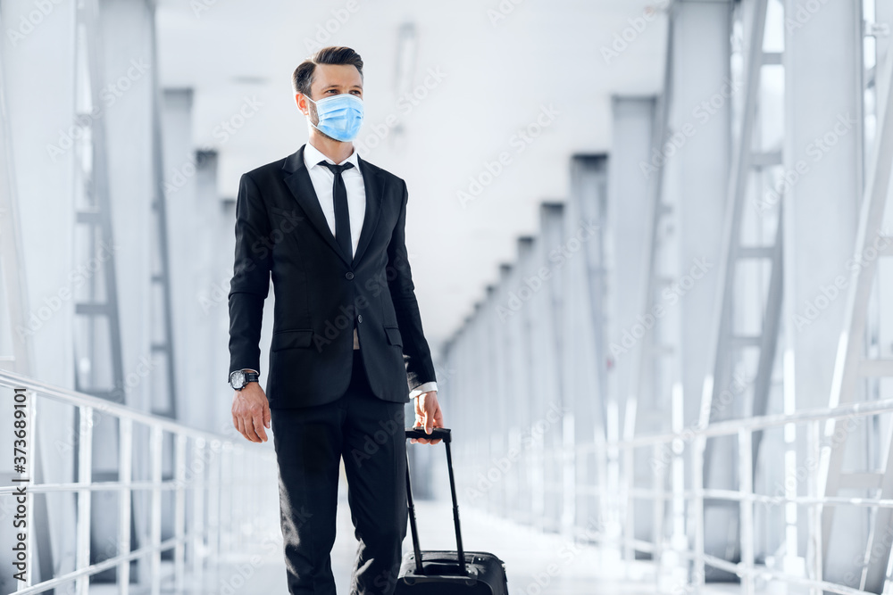 Handsome young businessman in protective mask walking by airport Handsome young businessman in protective mask walking by airport