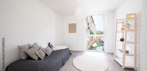 Nice bedroom with bookcase  a bed and lots of pillows. From the window you can see a canal in Venice