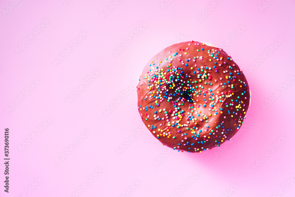 Overhead view of chocolate donut with sprinkles, on top of purple background, with available copy space. Overhead view of chocolate donut with sprinkles, on top of purple background, with available copy space.
