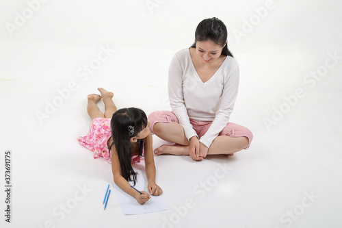 South East Asian mother daughter child study read write talk on floor white background pencil paper