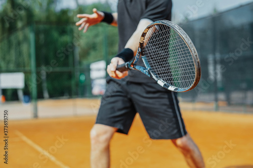 Close Up of Man Playing Tennis At Court And Beating The Ball With a Racket. Player is Hitting Ball With Racket While Playing Match © Akaberka