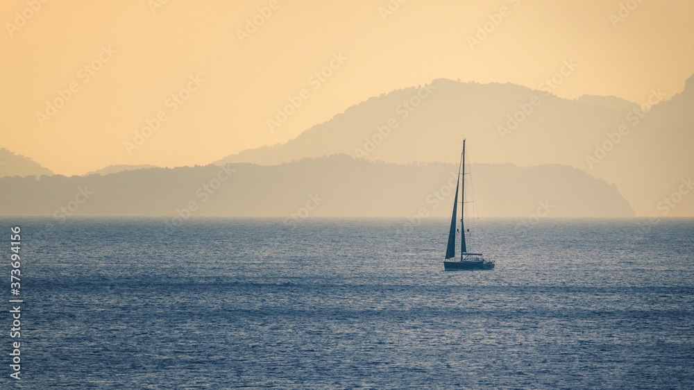 Single yacht on beautiful blue sea with distant mountains, Mallorca, Spain.