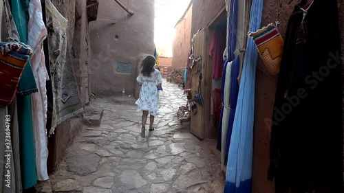 Unrecognizable woman walking through empty street of outdoor market stall in arabian ancient town Ait Benhaddou Morocco 