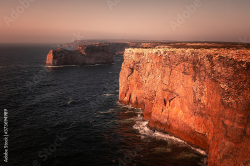 High red cliffs around Sao Vicente cape at south-west corner of Portugal, at the Algarve region.