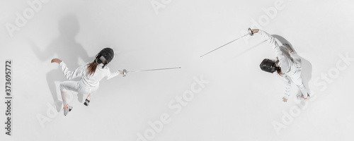 First. Teen girl in fencing costume with sword in hand on white background. Top view. Young female model practicing and training in motion, action. Copyspace. Sport, youth, healthy lifestyle. Collage.