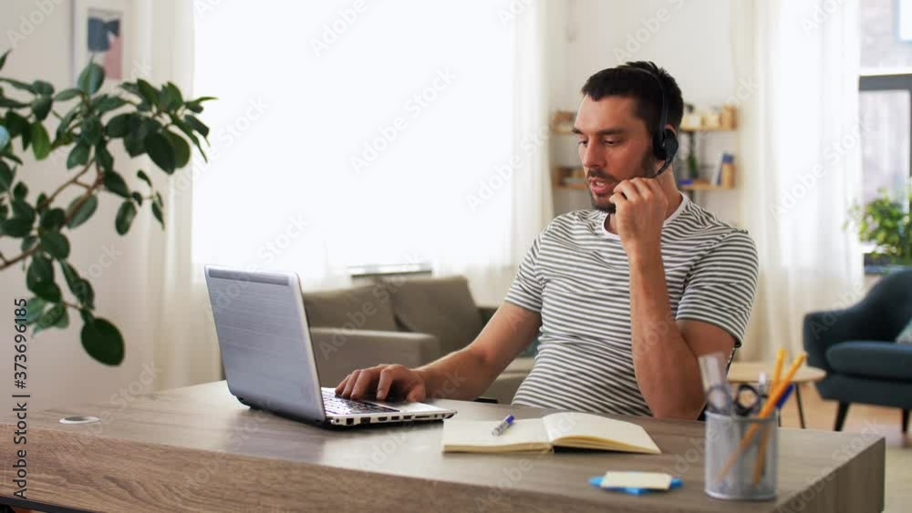 remote job, technology and people concept - man with headset and laptop computer having video conference at home office remote job, technology and people concept - man with headset and laptop computer having video conference at home office