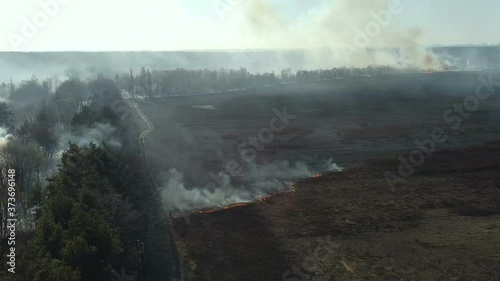 Huge clouds of smoke rise after field arson, burning trees and crops, aerial