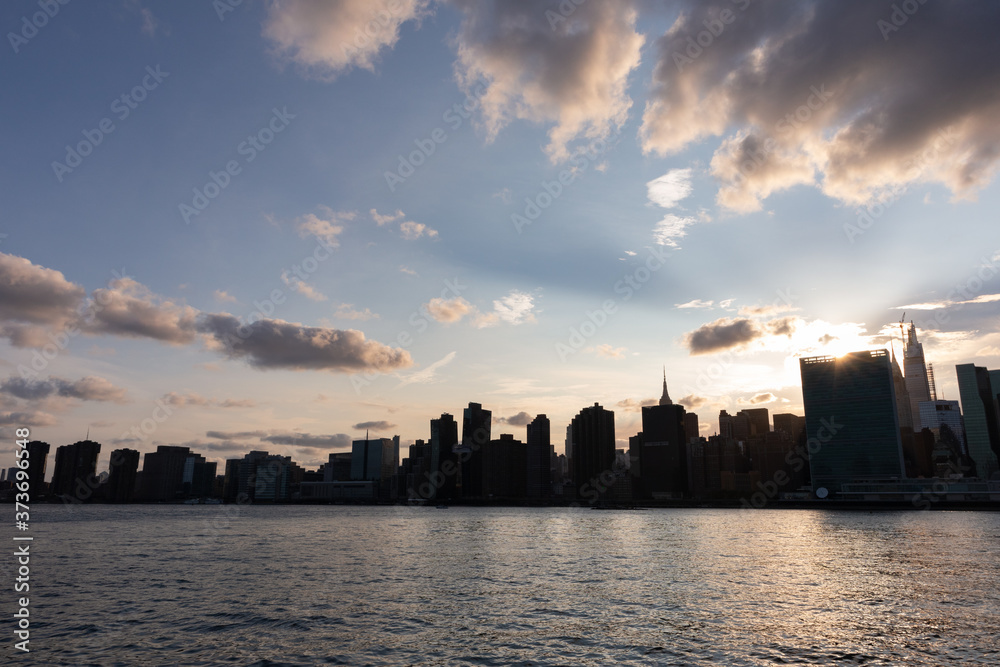 Naklejka premium Beautiful Silhouettes of Skyscrapers in the Midtown Manhattan Skyline during a Sunset along the East River in New York City