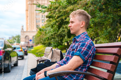 A young man sits on a bench in a Park against the background of old buildings in Moscow © KseniaJoyg