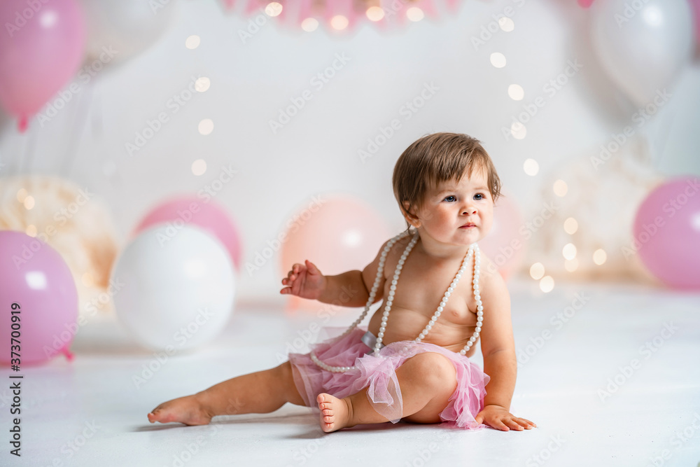 little girl in pink tutu skirt crawls on background with garlands and balloons