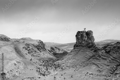 The silhouette of a hiker on top of a large rock at the Fairy Glen in Isle of Skye. 