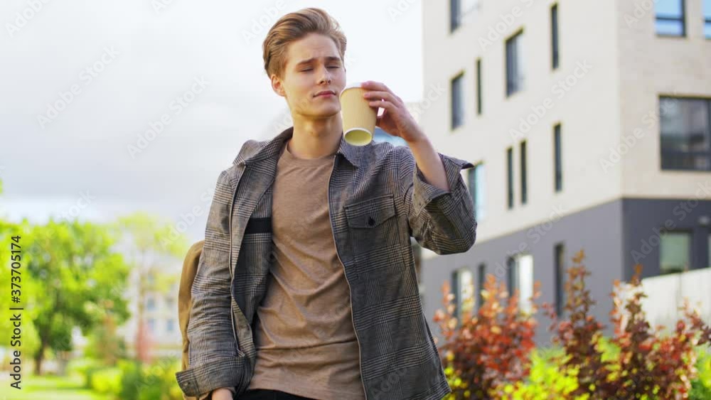 technology, leisure and people concept - young man or teenage boy with backpack drinking takeaway coffee in city technology, leisure and people concept - young man or teenage boy with backpack drinking takeaway coffee in city